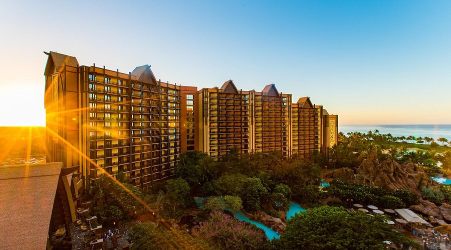 Aulani a Disney Resort and Spa, fachada del hotel al atardecer. Se percibe mar y alberca