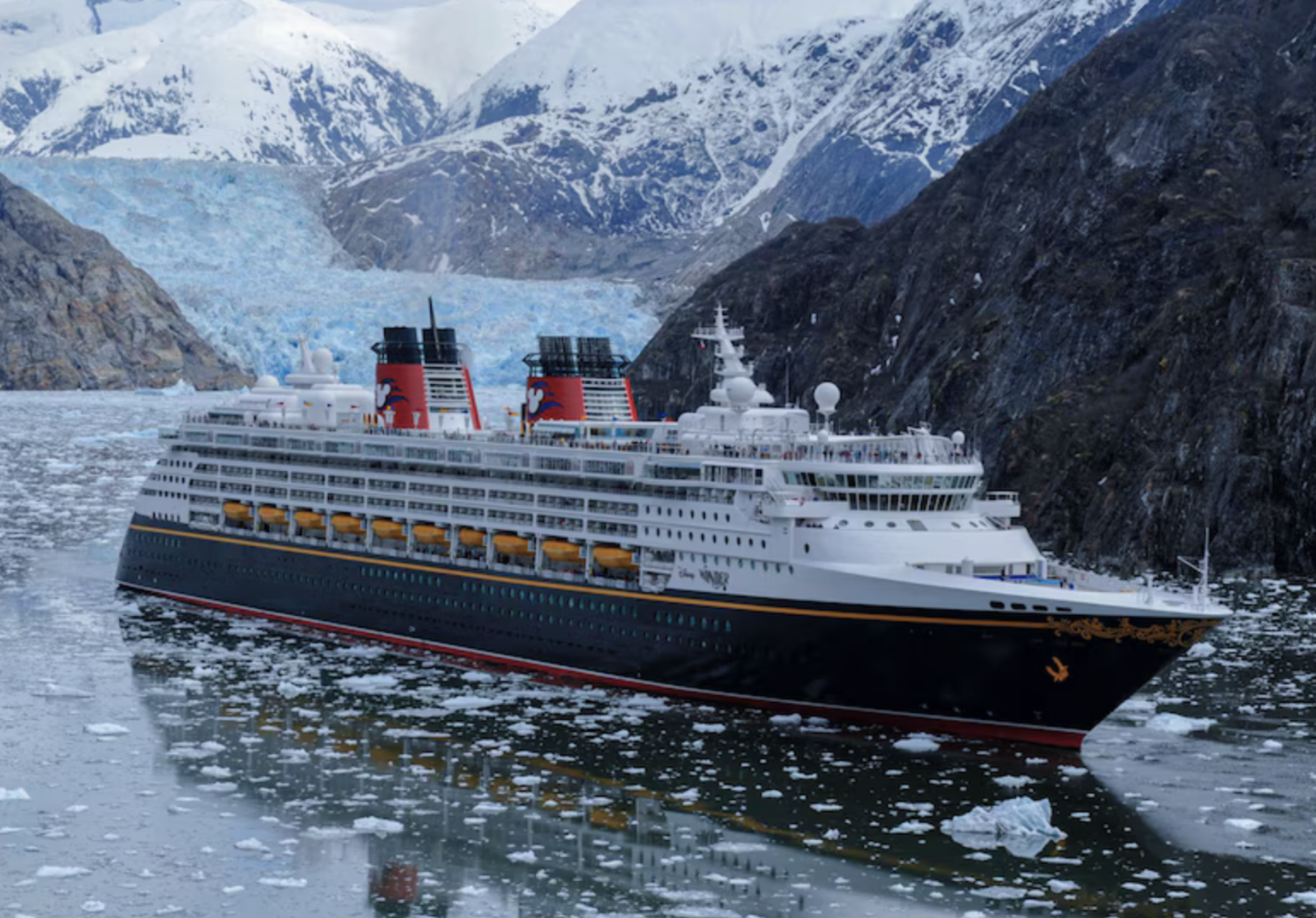 Disney Wonder de Disney Cruise Line navegando por Alaska. Montañas nevadas de fondo y hielo sobre el mar.