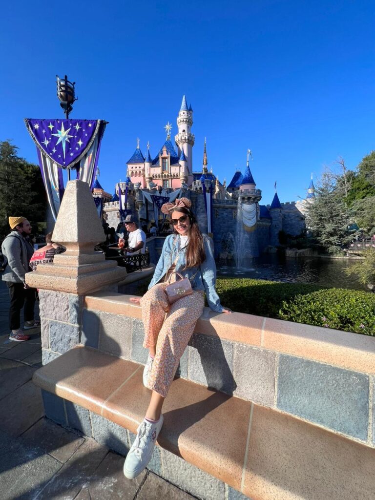 Mujer posando frente al castillo de La Bella Durmiente en parque Disneyland
