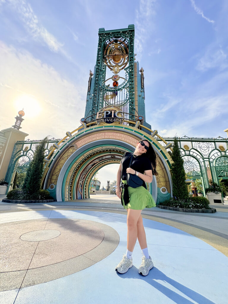 Mujer posando frente al arco principal de la entrada de Epic Universe en Universal Orlando Resort