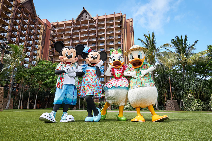 Personajes Disney posando frente a Aulani a Disney Resort and Spa. Mickey Mouse, Minnie Mouse, Daisy Duck y Doland Duck vistiendo ropa tradicional hawaiana.