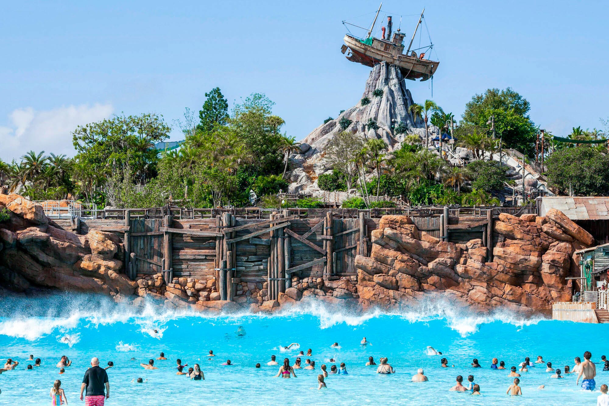 Vista de frente a la alberca principal de parque acuático Typhoon Lagoon en Walt Disney World. Se percibe la alberca de olas, el clásico barco icono del parque y vegetacion